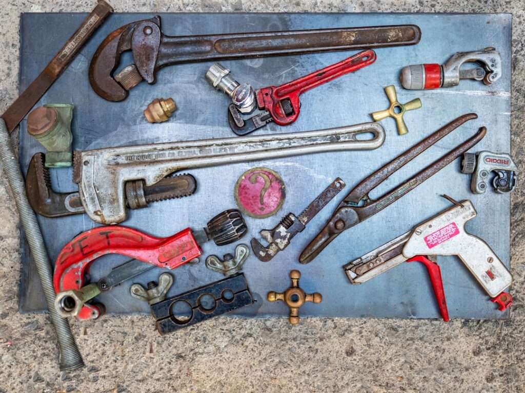 A homeowner assembling a plumbing emergency kit with tools and leak patching supplies on a kitchen counter.