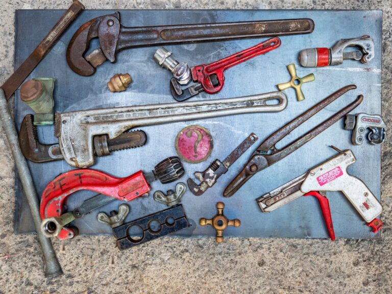 A homeowner assembling a plumbing emergency kit with tools and leak patching supplies on a kitchen counter.