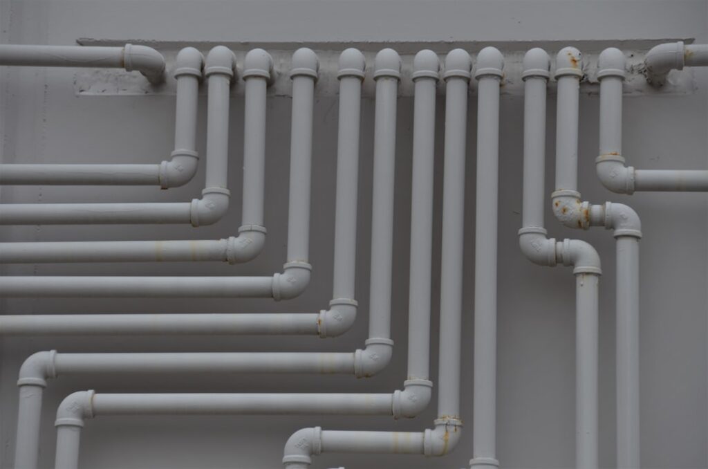 A close-up of pipes and valves under a kitchen sink with visible insulation and clean connections.