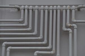 A close-up of pipes and valves under a kitchen sink with visible insulation and clean connections.