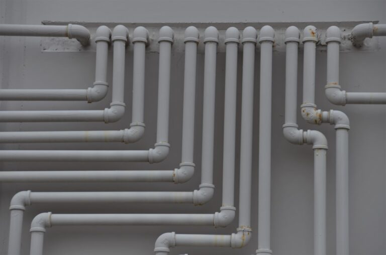 A close-up of pipes and valves under a kitchen sink with visible insulation and clean connections.