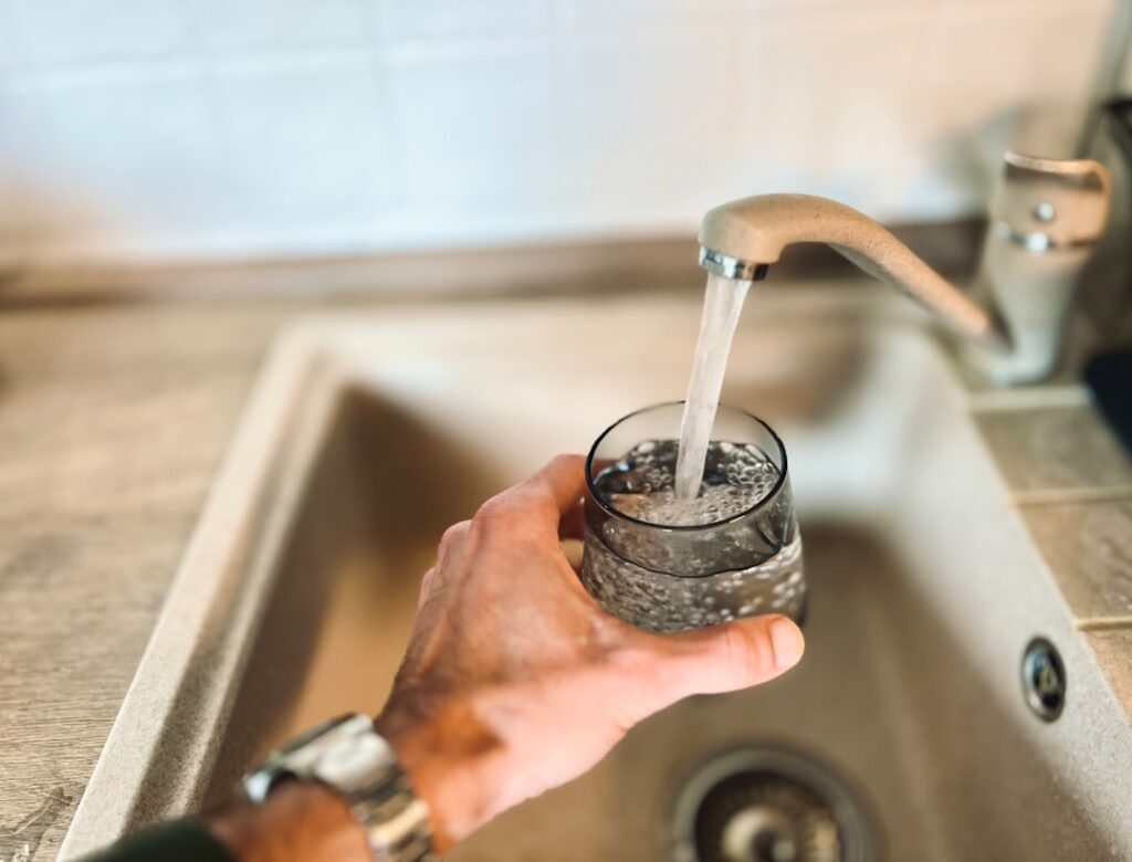 A close-up of a faucet with visible white mineral buildup around the spout and handle.