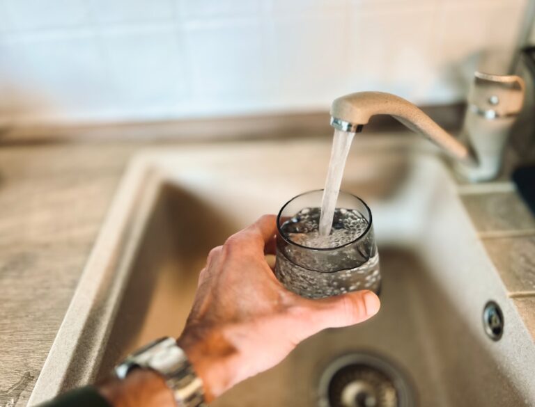 A close-up of a faucet with visible white mineral buildup around the spout and handle.
