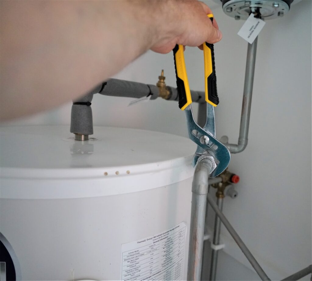 A homeowner checking a basement water pipe after hearing a loud plumbing noise nearby.