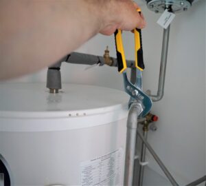 A homeowner checking a basement water pipe after hearing a loud plumbing noise nearby.