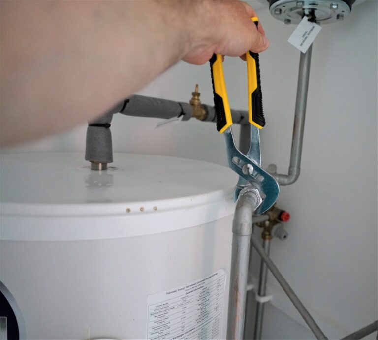 A homeowner checking a basement water pipe after hearing a loud plumbing noise nearby.